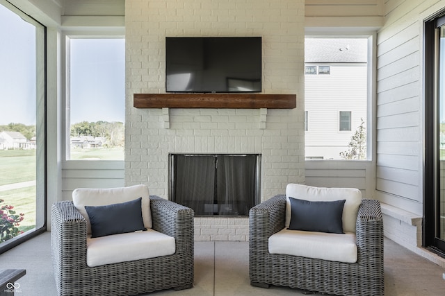 living area with wooden walls, a fireplace, and a healthy amount of sunlight