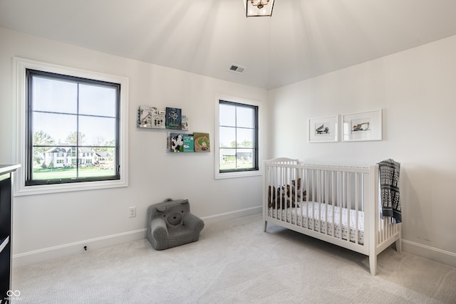 bedroom featuring a crib, lofted ceiling, and light carpet