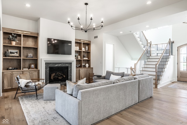 living room with light hardwood / wood-style flooring, a high end fireplace, and a chandelier