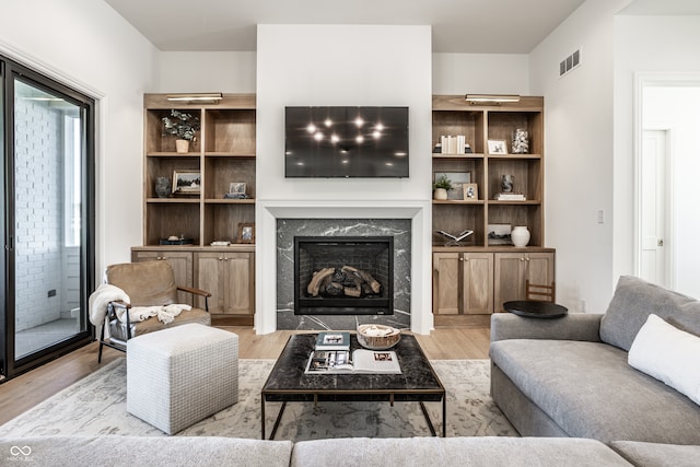 living room with a high end fireplace and light hardwood / wood-style floors