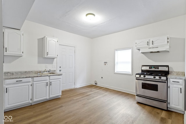 kitchen with stainless steel range, white cabinets, sink, and light wood-type flooring