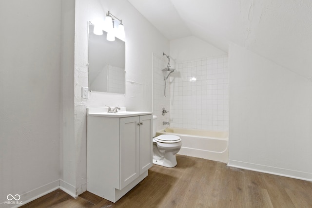 full bathroom featuring vanity, toilet, tiled shower / bath combo, vaulted ceiling, and hardwood / wood-style floors