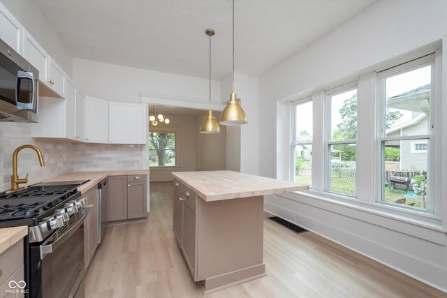 kitchen with pendant lighting, stainless steel appliances, plenty of natural light, and butcher block counters