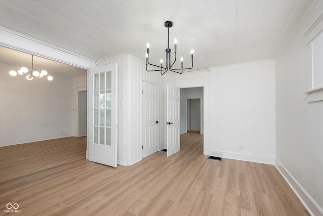 unfurnished dining area with ornamental molding, light wood-type flooring, and an inviting chandelier