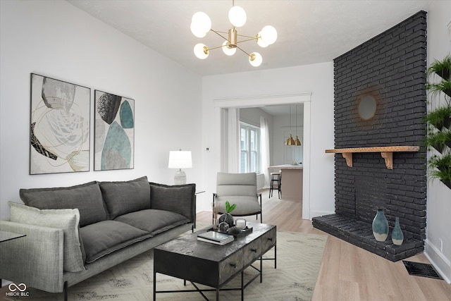 living room with a notable chandelier, a brick fireplace, light hardwood / wood-style floors, and a textured ceiling