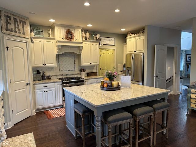 kitchen with a kitchen island, dark wood-type flooring, stainless steel appliances, and white cabinets