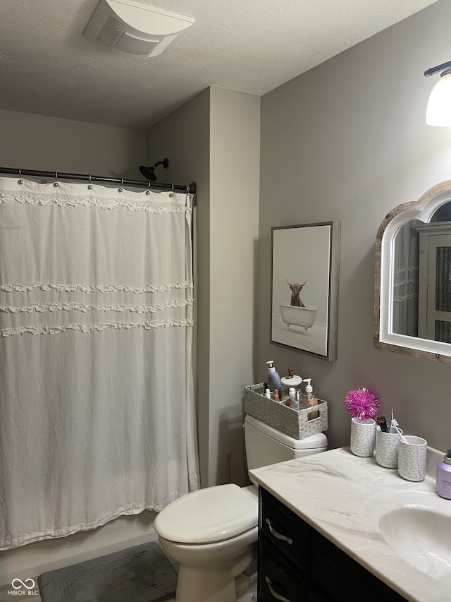 bathroom featuring a textured ceiling, vanity, and toilet