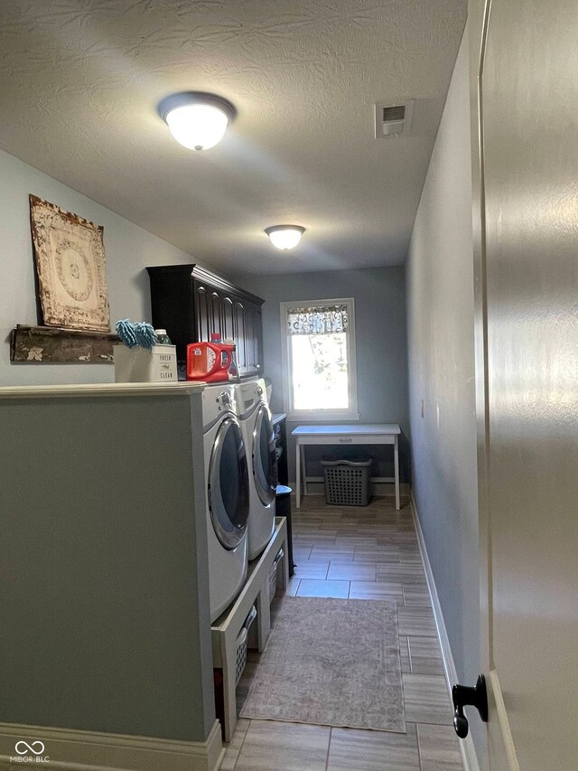 laundry room with a textured ceiling, separate washer and dryer, and cabinets