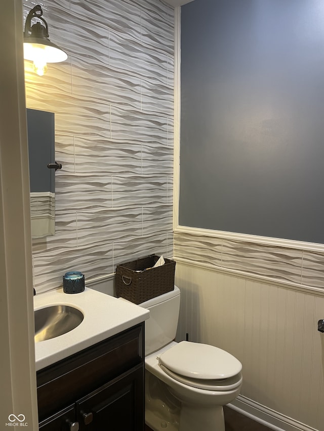 bathroom with vanity, tile walls, and toilet