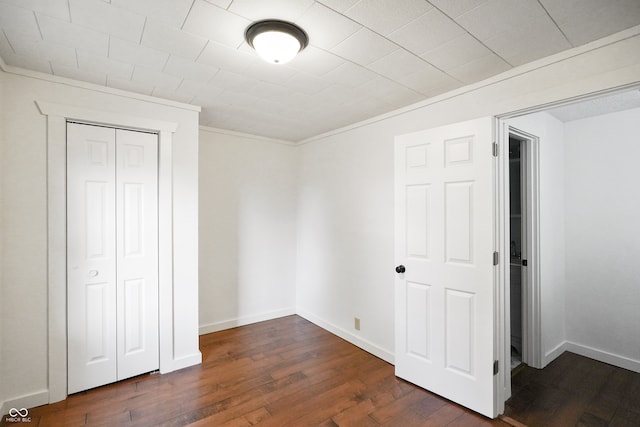 unfurnished bedroom featuring ornamental molding, a closet, and dark hardwood / wood-style floors