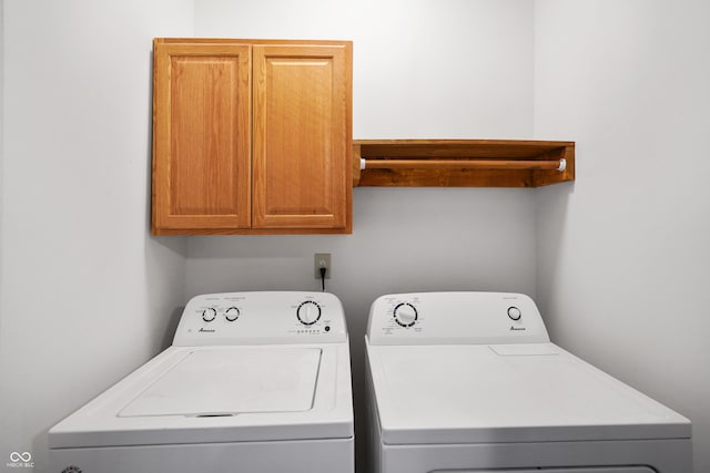 clothes washing area featuring washing machine and dryer and cabinets