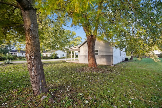 view of property exterior with a lawn and central AC