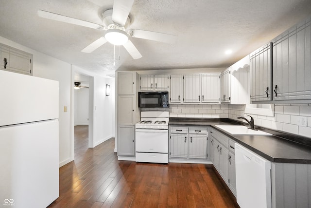 kitchen featuring a textured ceiling, sink, decorative backsplash, white appliances, and dark hardwood / wood-style flooring