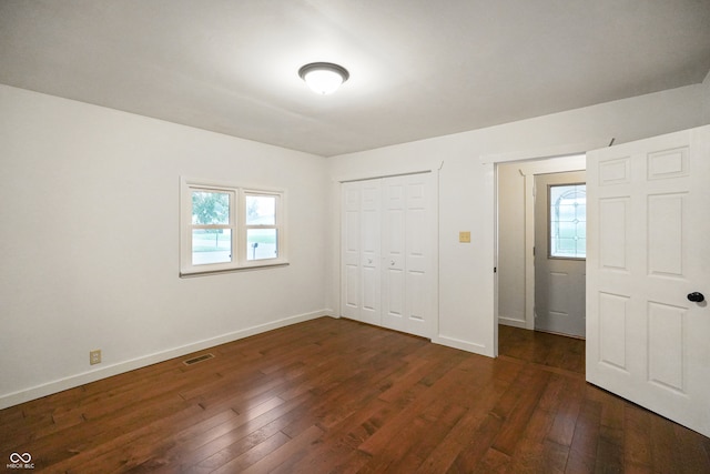 unfurnished bedroom with multiple windows and dark hardwood / wood-style floors