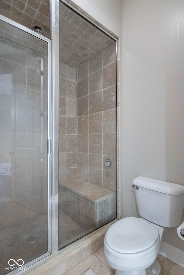 bathroom featuring tile patterned flooring, a shower with shower door, and toilet