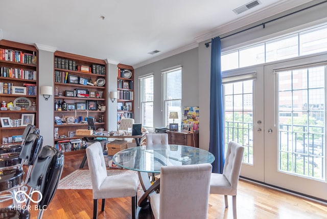 dining space with crown molding, light hardwood / wood-style flooring, french doors, and plenty of natural light