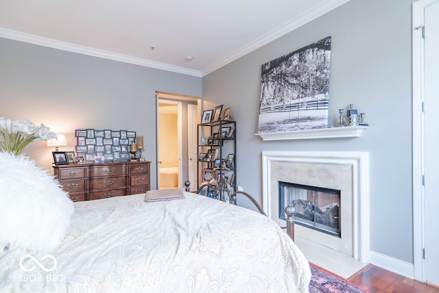 bedroom with a tile fireplace, crown molding, connected bathroom, and light wood-type flooring