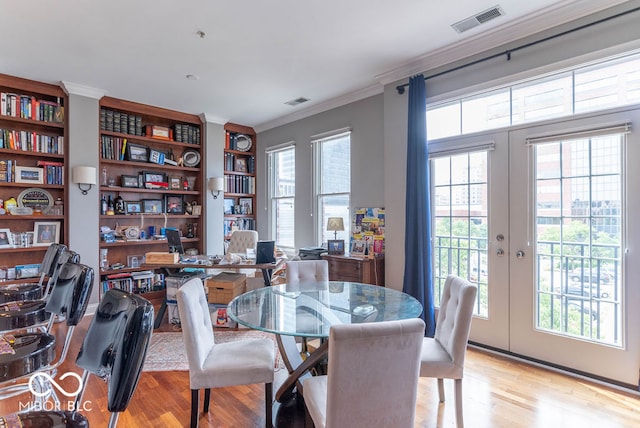 dining area featuring ornamental molding, light hardwood / wood-style flooring, french doors, and a wealth of natural light