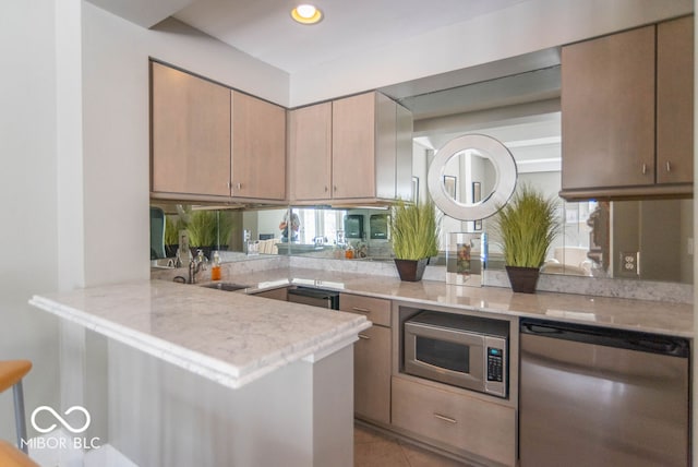 kitchen featuring appliances with stainless steel finishes, kitchen peninsula, light stone countertops, light tile patterned floors, and sink