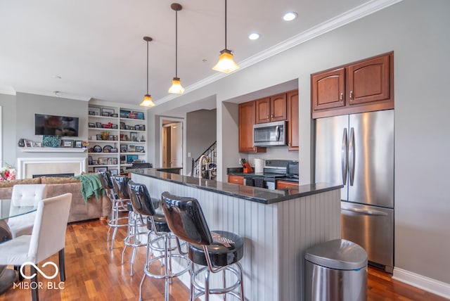 kitchen featuring a breakfast bar, stainless steel appliances, decorative light fixtures, and dark hardwood / wood-style flooring