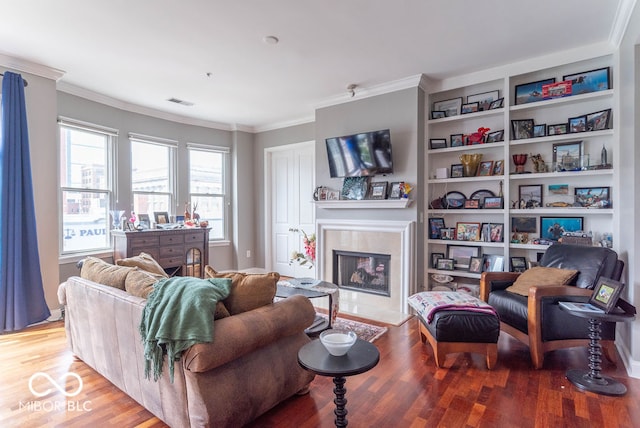 living room with built in shelves, crown molding, hardwood / wood-style floors, and a tile fireplace