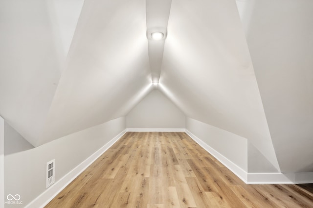 additional living space featuring light wood-type flooring and lofted ceiling