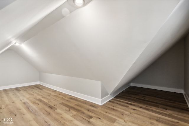 additional living space with lofted ceiling and hardwood / wood-style flooring