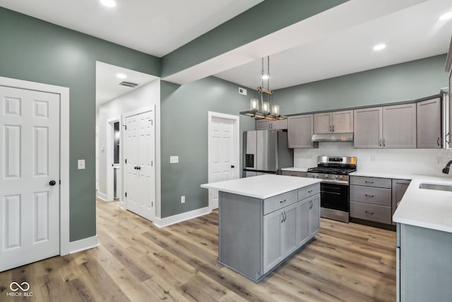 kitchen featuring decorative light fixtures, appliances with stainless steel finishes, a center island, and gray cabinetry