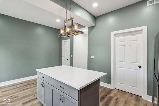 kitchen featuring gray cabinets, a center island, decorative light fixtures, hardwood / wood-style floors, and a notable chandelier