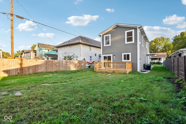 rear view of property with central air condition unit, a deck, and a yard