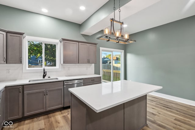 kitchen with light hardwood / wood-style floors, sink, a kitchen island, decorative backsplash, and stainless steel dishwasher