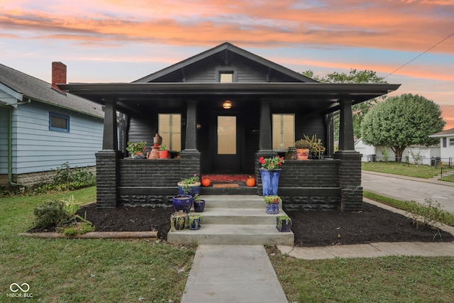 view of front of house featuring covered porch and a yard