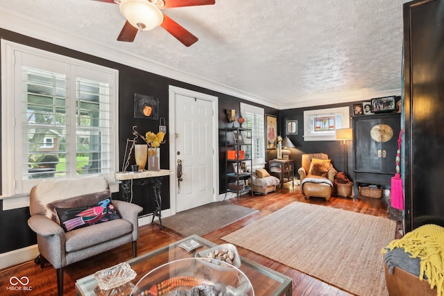 living room with a textured ceiling, crown molding, dark hardwood / wood-style flooring, and ceiling fan