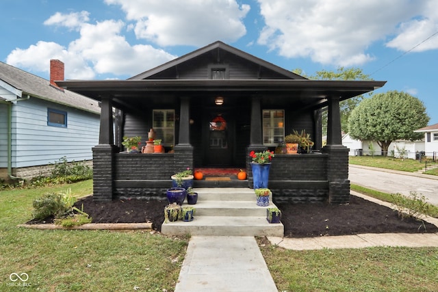 bungalow-style house with a front lawn and covered porch