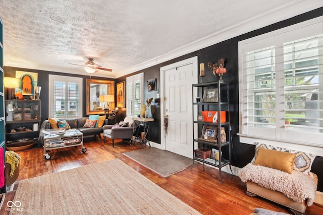 living room with a textured ceiling, ornamental molding, ceiling fan, and hardwood / wood-style flooring