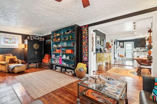 living room featuring a textured ceiling, ornamental molding, and hardwood / wood-style flooring