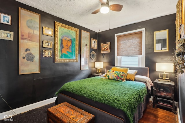 bedroom with a textured ceiling, dark wood-type flooring, and ceiling fan