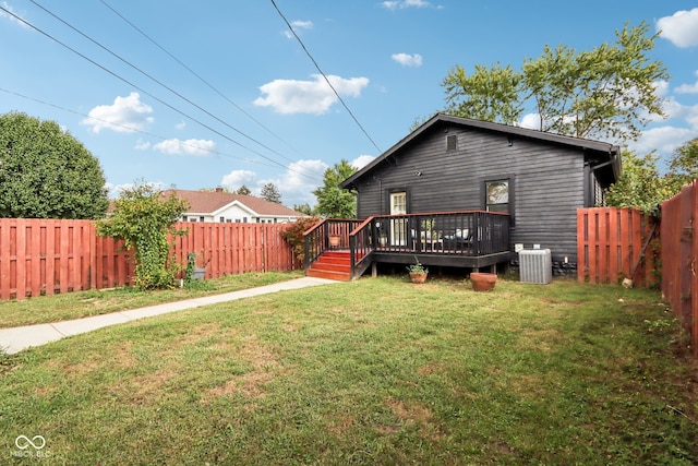 rear view of property featuring a lawn, central AC, and a wooden deck