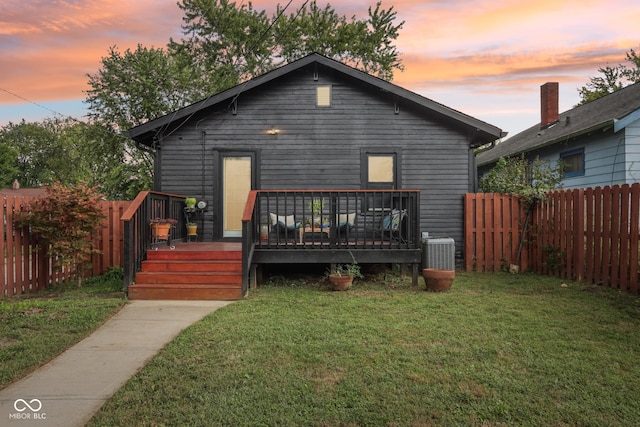 back house at dusk with a deck and a yard