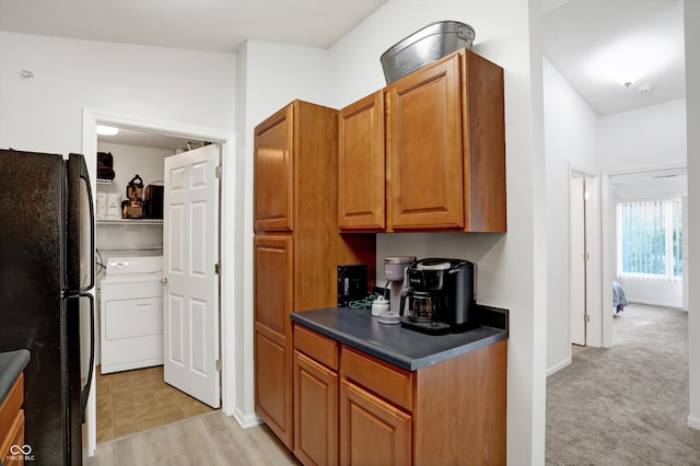 kitchen with washer / clothes dryer, light colored carpet, and black fridge