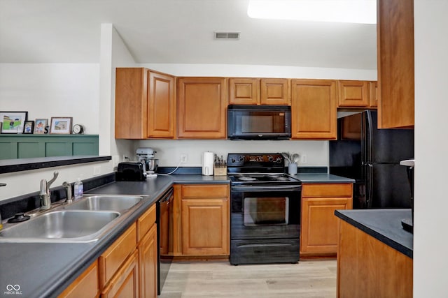 6517 Emerald Hill Ct Apt 312, Indianapolis, IN 46237 - kitchen with visible vents, a sink, light wood-type flooring, dark countertops, and black appliances