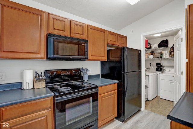 kitchen with light wood-type flooring, black appliances, vaulted ceiling, and washer and clothes dryer