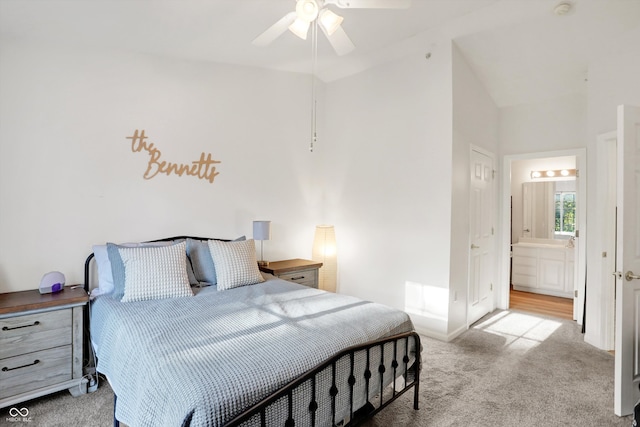 bedroom with ceiling fan, light colored carpet, and ensuite bath