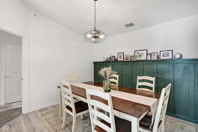 dining room with a notable chandelier, light hardwood / wood-style flooring, and vaulted ceiling