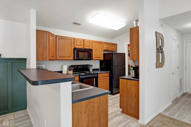 kitchen with light wood-type flooring, kitchen peninsula, and black appliances