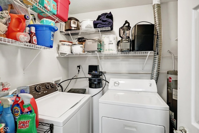 laundry room featuring water heater, a textured ceiling, and washer and clothes dryer