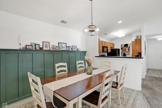 dining room with light wood-type flooring, vaulted ceiling, and an inviting chandelier