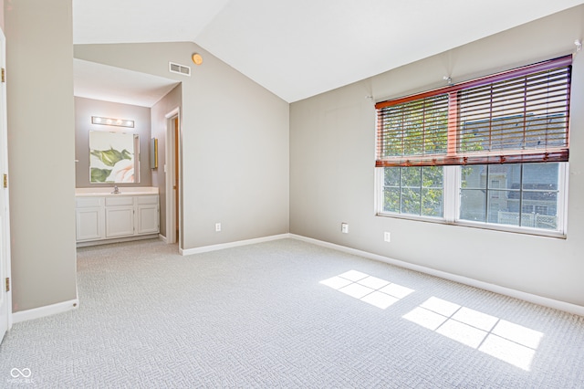 carpeted empty room featuring vaulted ceiling and sink