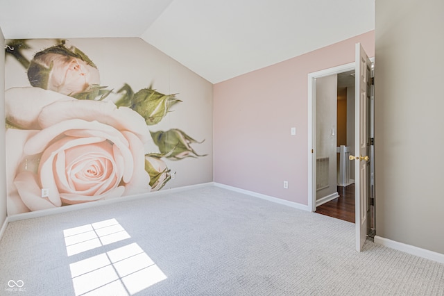 carpeted spare room featuring vaulted ceiling