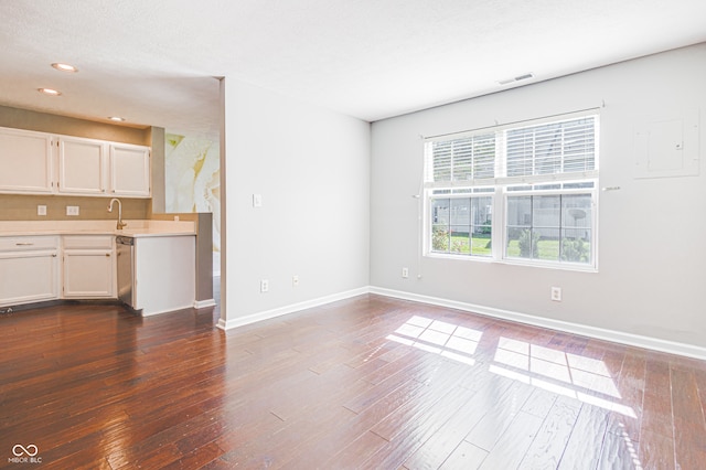 unfurnished living room with dark hardwood / wood-style floors, sink, a textured ceiling, and electric panel